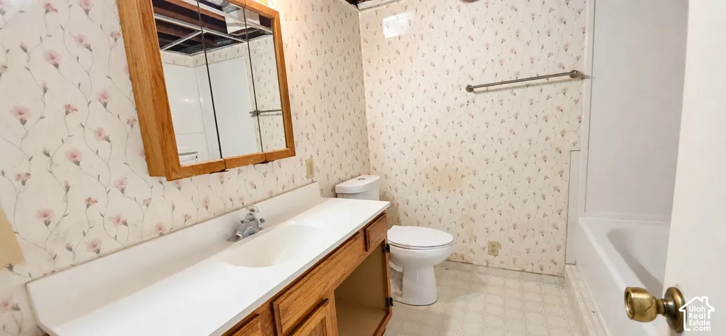 Bathroom featuring a single vanity with wood-finish cabinetry, a white countertop, and an integrated white sink