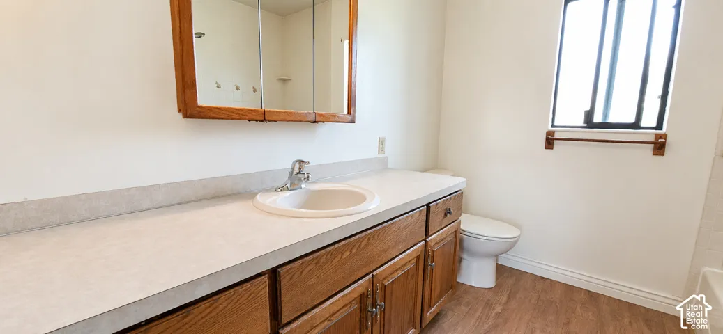 Bathroom featuring a wood-finish vanity with ample counter space, an integrated sink, and a framed medicine cabinet