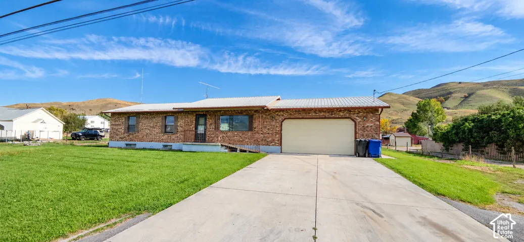 Brick exterior with a metal roof, attached garage, and concrete driveway
