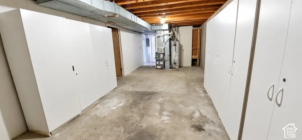 Extensive built-in storage cabinetry, exposed ceiling joists, concrete flooring, and utility infrastructure