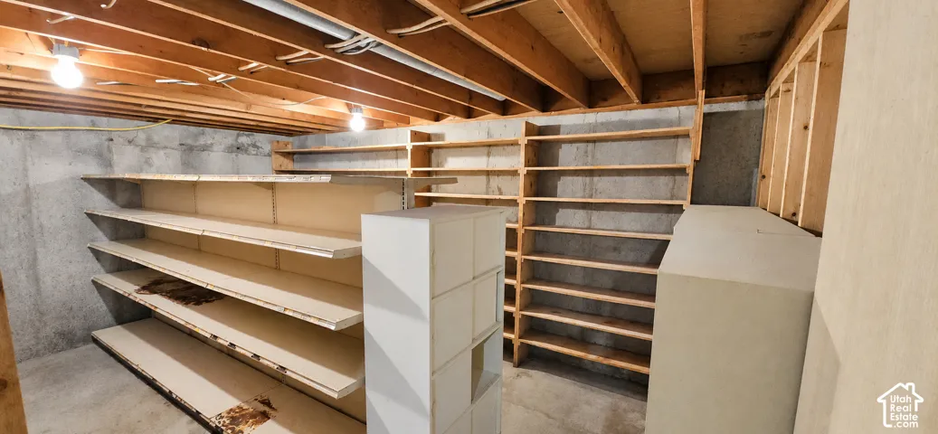 Extensive built-in shelving units, exposed ceiling joists, concrete walls, and overhead lighting
