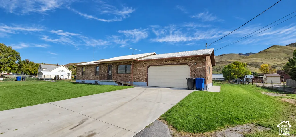 Brick exterior with a metal roof, attached garage, and a concrete driveway
