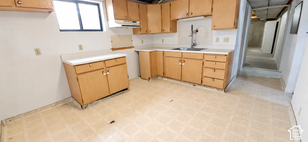 Kitchen featuring wood-finish cabinetry, a stainless steel sink, and a white countertop