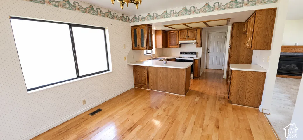 Kitchen featuring wood-finish cabinetry, white countertops, built-in stove, and a central island