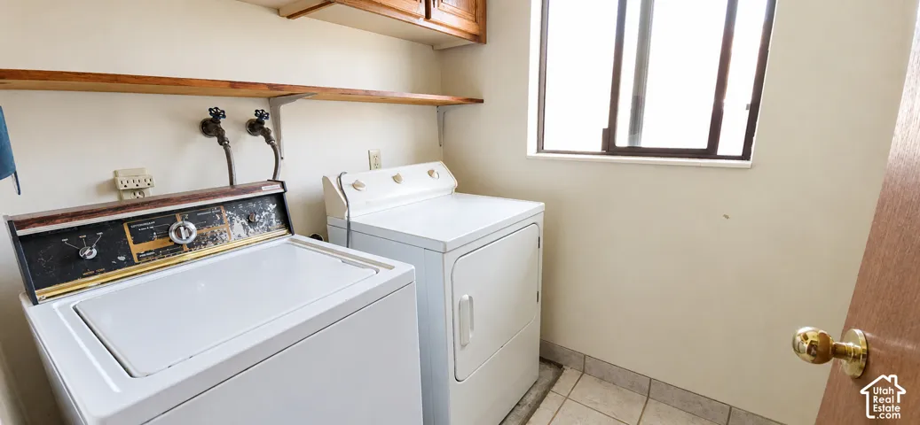Utility area with tiled flooring, wood-finish shelving, and upper wood-finish cabinetry