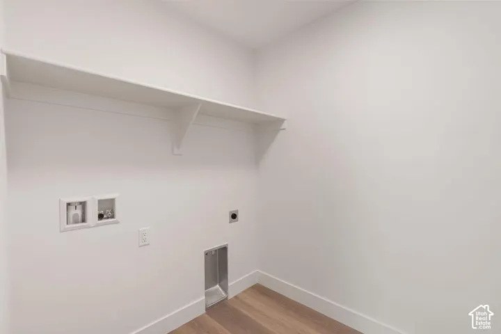 Dedicated laundry area featuring a built-in shelf, appliance hookups, and wood-finish flooring