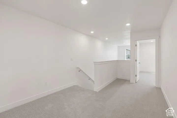 Upper-level landing featuring recessed lighting, a neutral carpet, white walls, and a staircase with a handrail