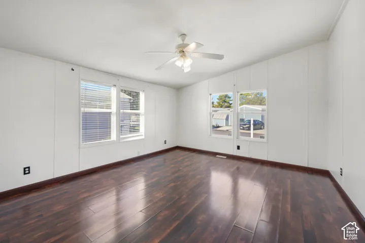 Wood-finish flooring, white walls, multiple windows, and a ceiling fan
