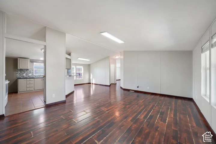 Hardwood-finish flooring throughout, light gray wall panels, and a kitchen featuring a mosaic tile backsplash and light-toned cabinetry