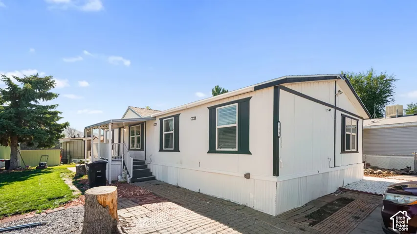 White siding exterior with dark trim accents, covered entry, and paved driveway