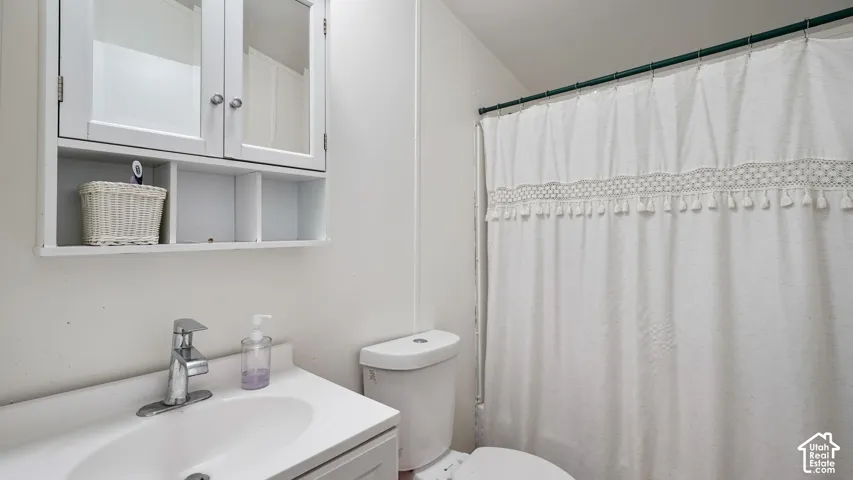 White vanity with integrated sink, chrome faucet, and white two-door medicine cabinet with open shelving