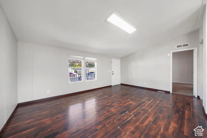 Wood-finish flooring throughout, light gray walls, white trim, and a white entry door