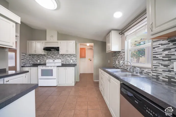 Kitchen with white cabinetry, dark countertops, a mosaic tile backsplash, stainless steel double basin sink, and tile flooring