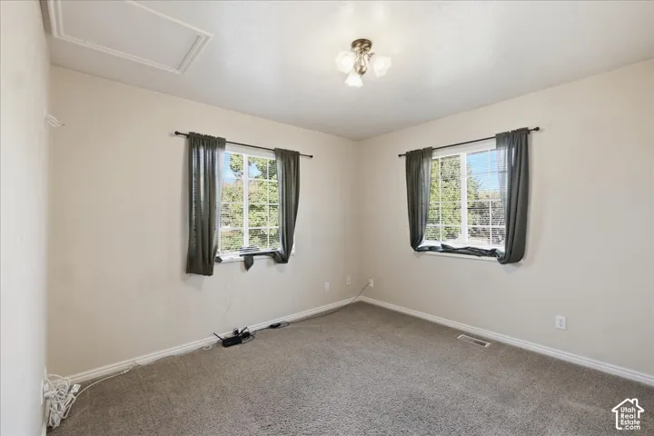 Bedroom #3. Neutral-toned interior room featuring wall-to-wall carpeting, dual windows with grid mullions, and a three-bulb flush-mount ceiling fixture