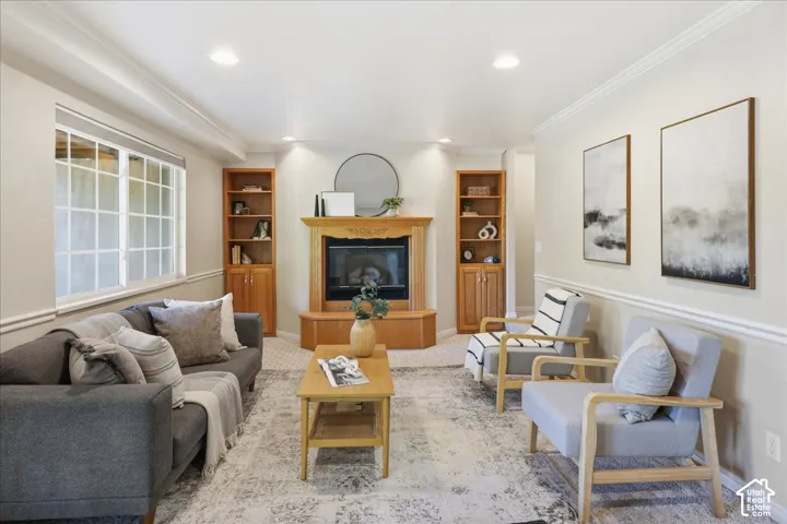 Fireplace with wood mantle and hearth, flanked by custom built-in wooden cabinetry, recessed lighting, and crown molding