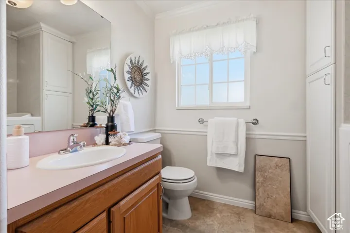 Primary bath. Bathroom featuring a wood-finish vanity with a solid-surface countertop, an integrated oval sink, full-height built-in cabinetry, and tile flooring