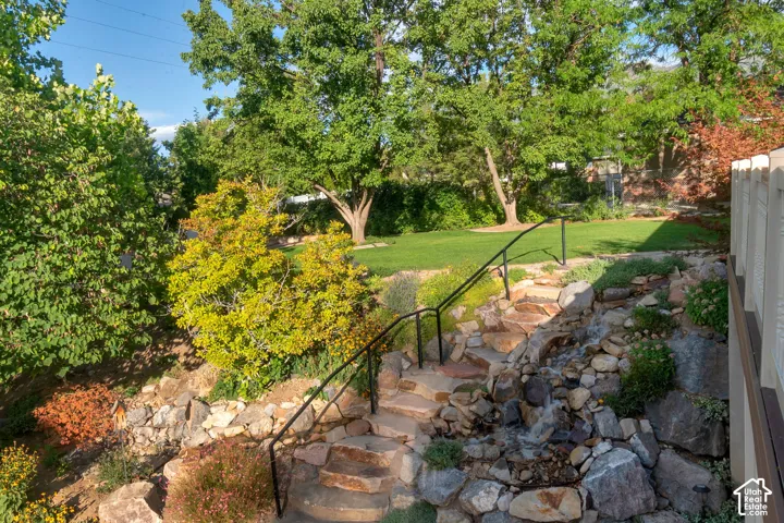 Stone path stairway featuring a metal handrail, rock garden, and water feature