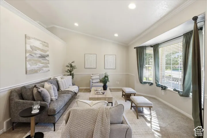 Living space featuring vaulted ceilings, recessed lighting, crown molding, chair rail trim, and a multi-paneled bay window