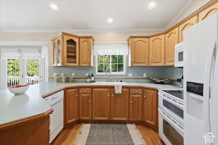 Kitchen featuring natural wood cabinetry, solid surface countertops, recessed lighting, integrated double-door refrigerator, and wood-finish flooring
