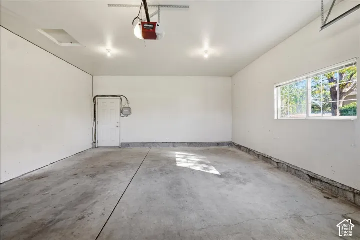 Finished garage featuring a concrete floor, painted interior walls, ceiling-mounted automatic door opener, and a single-pane sliding window