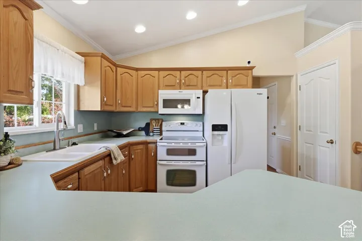 Kitchen featuring wood cabinetry, solid-surface countertops, vaulted ceilings, recessed lighting, and white appliances