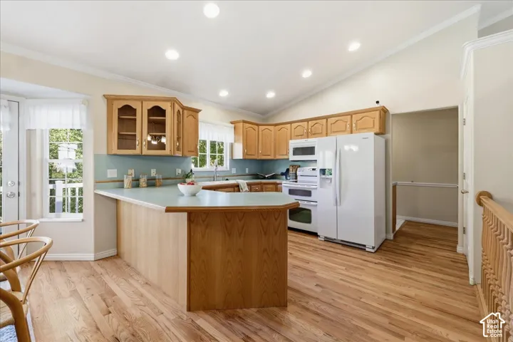 Kitchen featuring wood-finish cabinetry, light-toned countertops, wood-finish flooring, recessed lighting, and vaulted ceilings