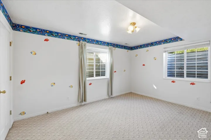 Bedroom #4. Spacious bedroom featuring neutral carpeting, recessed ceiling lighting, and two egress windows with corrugated metal window wells