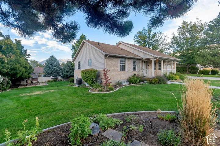 Brick and siding exterior with a covered front porch, established landscaping, and a manicured lawn