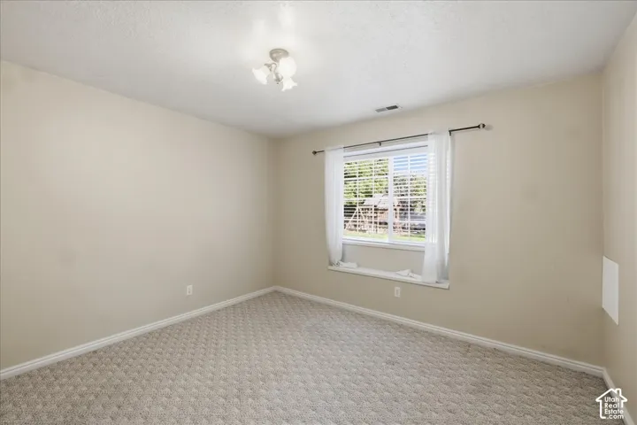 Bedroom #2. Neutral-toned interior space featuring wall-to-wall carpeting, a multi-light flush-mount ceiling fixture, and a window with a built-in sill