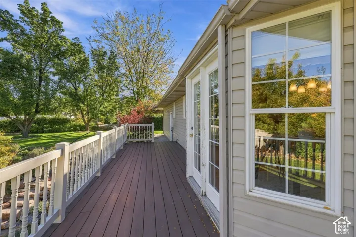 Elevated deck featuring composite plank flooring, white railing, horizontal lap siding, and glass-paneled double doors