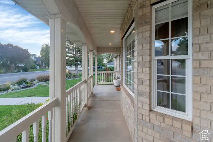Brick exterior with white window frames, a covered porch, white balusters, and recessed ceiling lighting