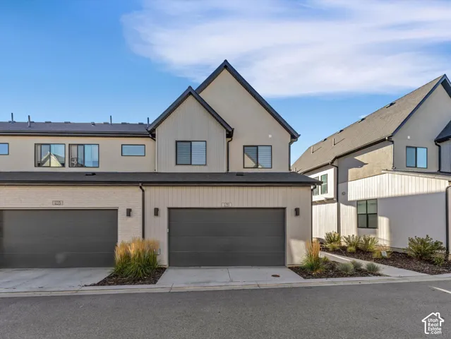 Contemporary townhome featuring a two-car garage, multiple large windows, and a combination of horizontal siding and stucco exterior finishes