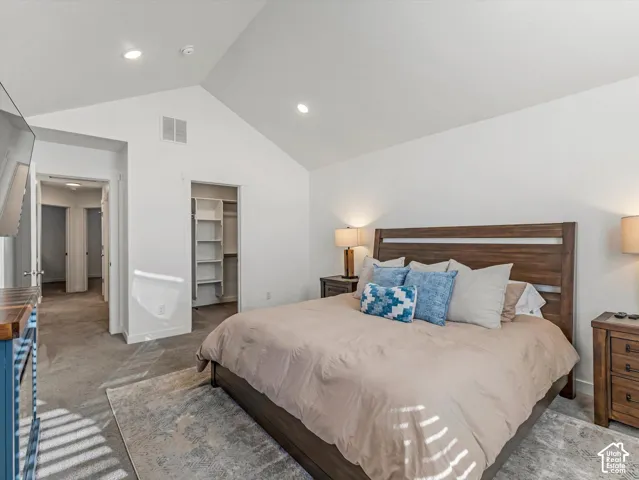 Vaulted ceiling with recessed lighting, carpeted flooring, and built-in closet shelving