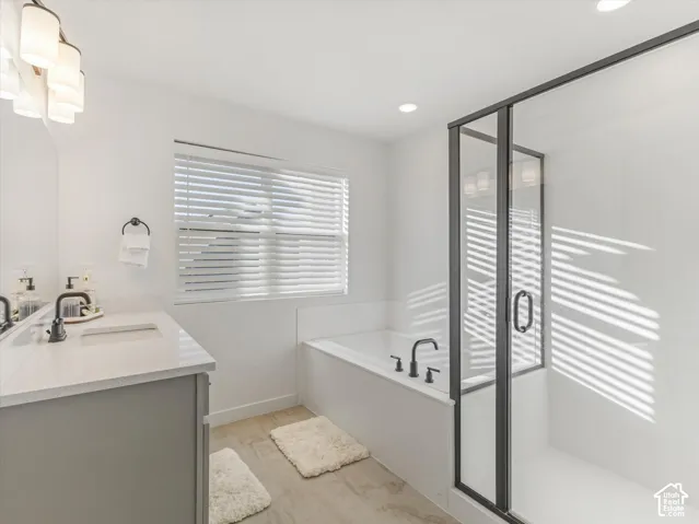 Modern bathroom featuring a built-in tub, separate shower with a dark-framed glass enclosure, and a vanity with a white countertop and dark faucet