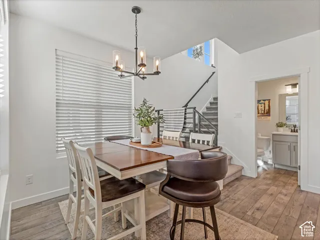 Wood-finish flooring, staircase with metal railing, black iron chandelier, window with blinds, recessed lighting