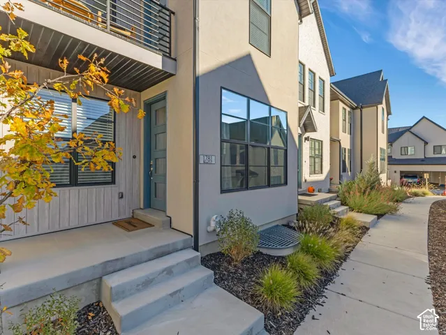 Contemporary exterior featuring a panel-paneled entry door, concrete steps, and a second-story balcony with metal railings