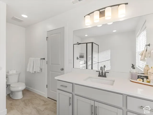 Light-colored flooring, vanity with light-colored countertop, under-mount sink, black-finish faucet, and a wall-mounted light fixture