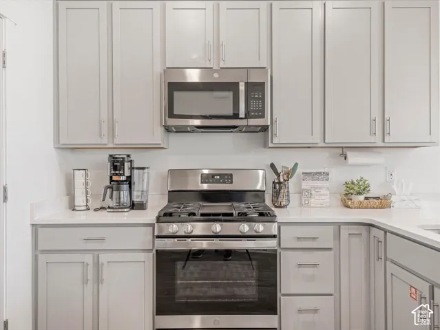 Light gray cabinetry, stainless steel appliances, white countertops, and a gas range