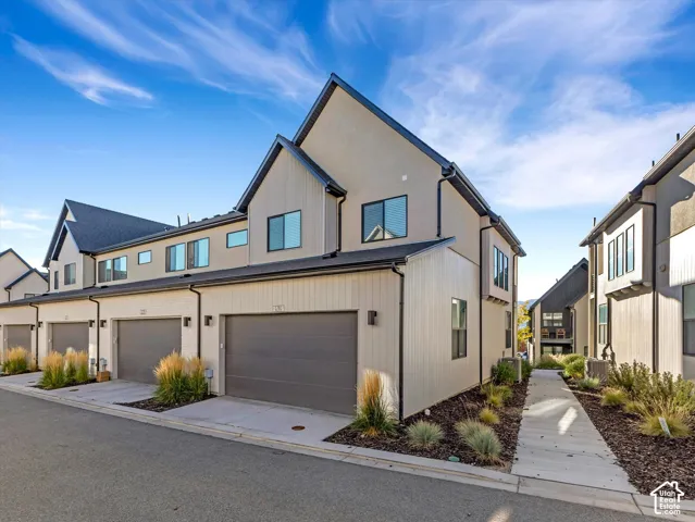 Modern townhome exterior featuring an attached garage, vertical siding, and stucco finishes