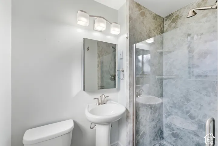 Pedestal sink with chrome faucet, wall-mounted mirror, and vanity lighting