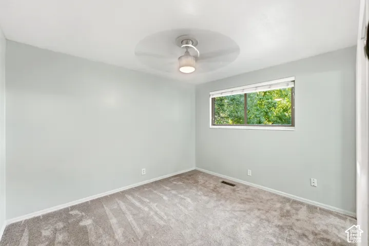 Wall-to-wall carpeting with light-colored walls and a ceiling-mounted fan