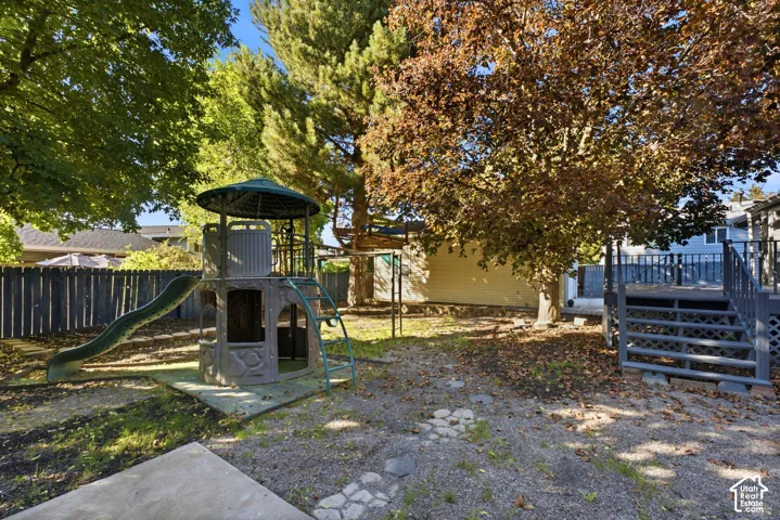 Spacious backyard featuring a large elevated deck, mature trees, and a privacy fence