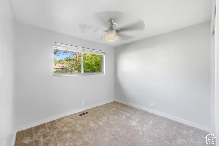 Recessed window with blinds, overhead ceiling fan with lighting, and light-toned wall-to-wall carpeting