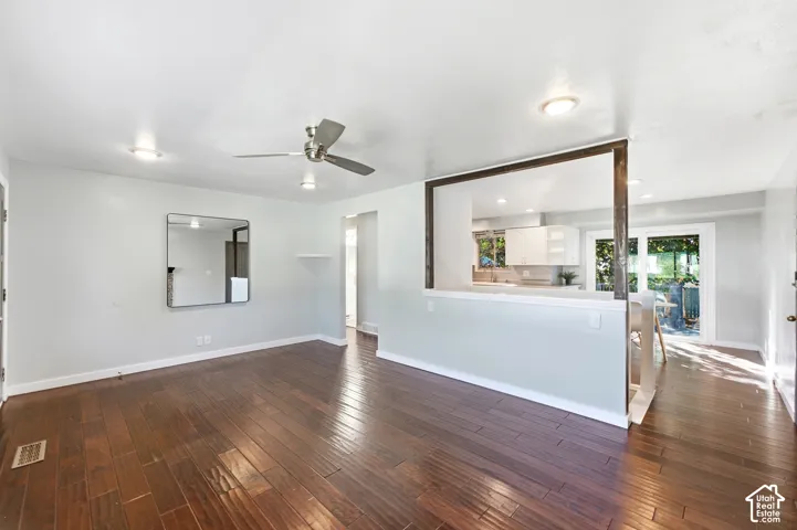 Wood-finish flooring, recessed lighting, ceiling fan, pass-through opening to kitchen, and a sliding glass door
