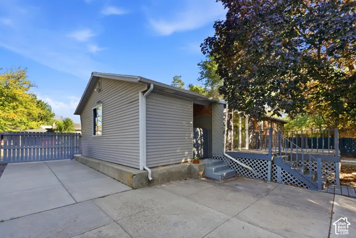 Siding exterior with a single window, concrete patio, and a privacy fence