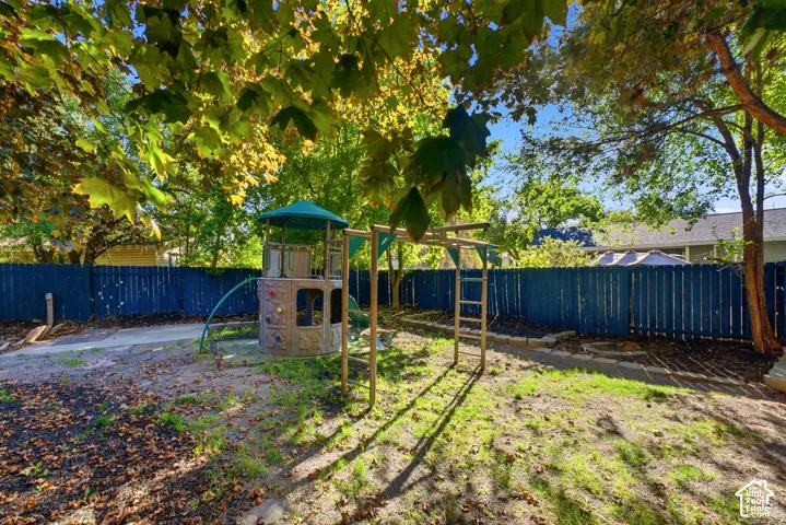 Fenced yard with mature trees, green space, and a blue privacy fence