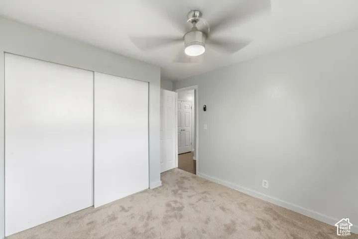 Wall-to-wall carpeting and a ceiling fan with integrated lighting