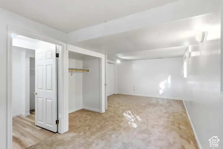 Carpeted flooring, white walls, built-in open closet, hinged door, and wall-mounted light fixtures