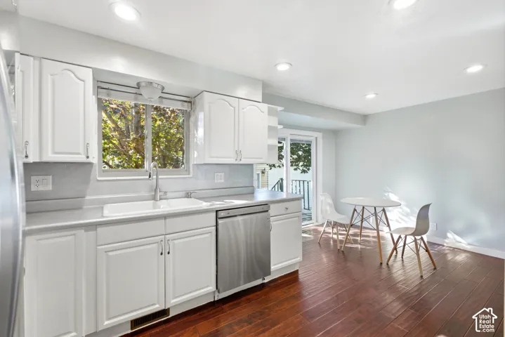 White cabinetry, stainless steel dishwasher, a single basin sink, a sliding glass door, and recessed lighting