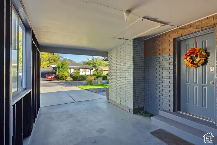 Covered entry with gray painted concrete steps and a paneled entry door